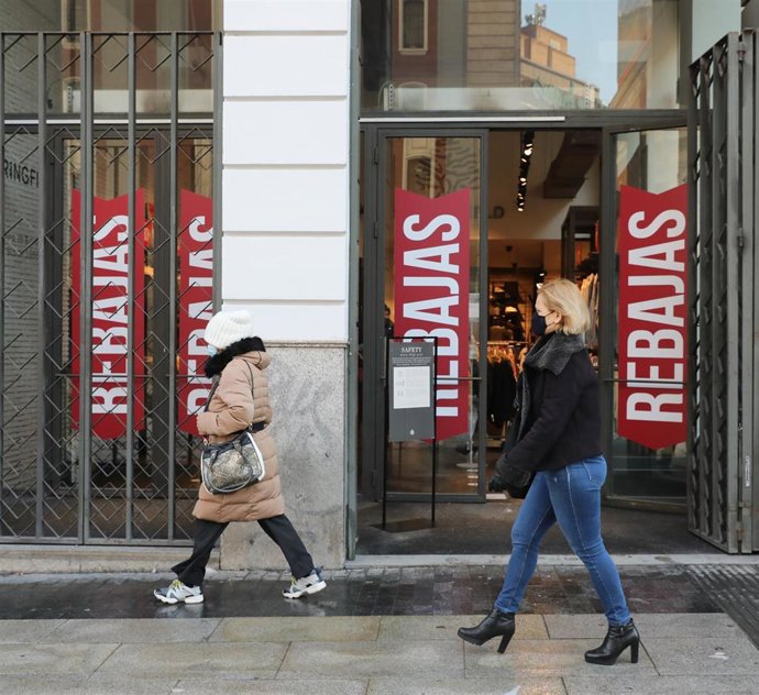 Archivo - Transeúntes pasan por delante de un establecimiento durante la temporada de rebajas, en una imagen de archivo.