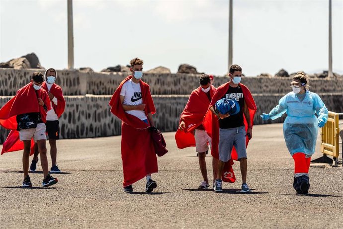 Archivo - Un trabajador de la Cruz Roja con varios de los 34 migrantes que han sido rescatados por Salvamento Marítimo, cuando iban en una patera, en el Muelle de La Cebolla, a 1 de septiembre de 2021, en Lanzarote, Islas Canarias (España).