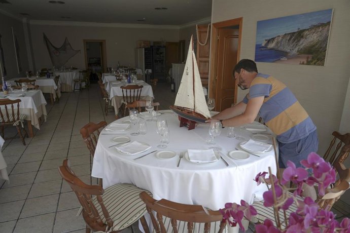 Archivo - Un hombre prepara una mesa de su restaurante el día en Getxo (Bizkaia)