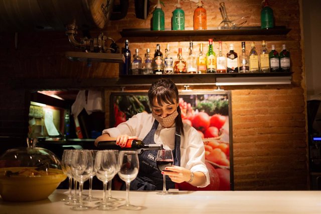 Archivo - Una camarera sirve una copa de vino en el interior de un bar en una calle céntrica de Barcelona, a 14 de octubre de 2021, en Barcelona, Catalunya (España). A partir de este viernes en Cataluña se terminarán las limitaciones de aforo en los equip