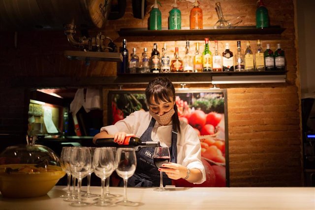 Archivo - Una camarera sirve una copa de vino en el interior de un bar de Barcelona