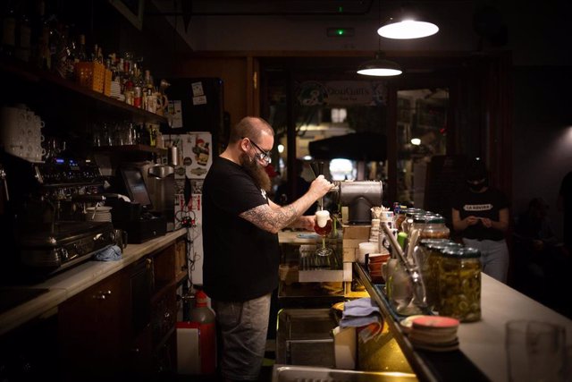 Archivo - Un camarero sirve una cerveza en el interior de un bar en una imagen de archivo.