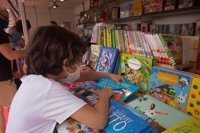 Archivo - Un niño ojea libros en la Feria del Libro de Mérida.