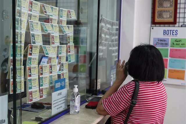 Archivo - Una mujer compra lotería en una Administración en Manises.
