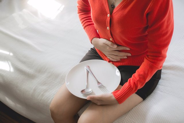 Archivo - Mujer con hinchazon tras comer. Comida pesada. Dolor de estómago. Foto recurso.