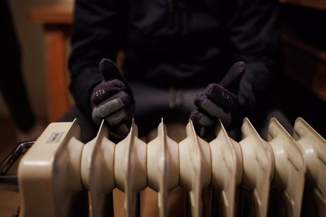Archivo - Una persona se calienta las manos en un radiador eléctrico.
