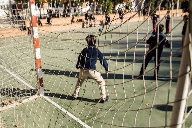 Archivo - Varios niños juegan al fútbol en el patio de un colegio