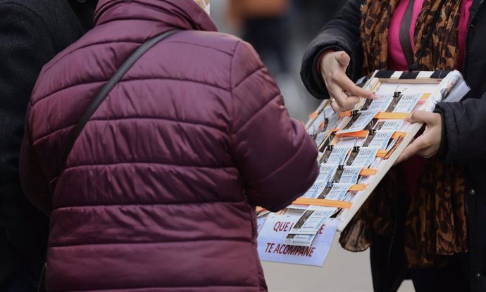 Una mujer compra un décimo de lotería a una vendedora ambulante, tres días antes del Sorteo de La Lotería del Niño