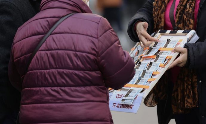 Una mujer compra un décimo de lotería a una vendedora ambulante, tres días antes del Sorteo de La Lotería del Niño, a 3 de enero de 2022, en Madrid, (España)