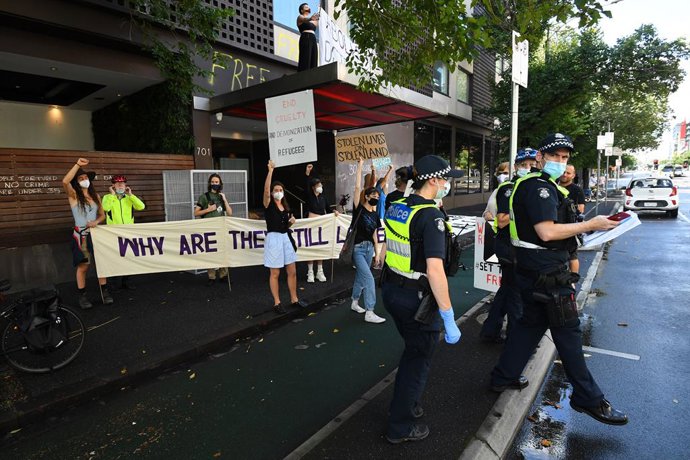 Victorian Police officers and protesters are seen outside of the Park hotel quarantine facility where it is believed Serbian tennis player Novak Djokovic is being detained in Melbourne, Thursday, January 6, 2022. (AAP Image/James Ross) NO ARCHIVING