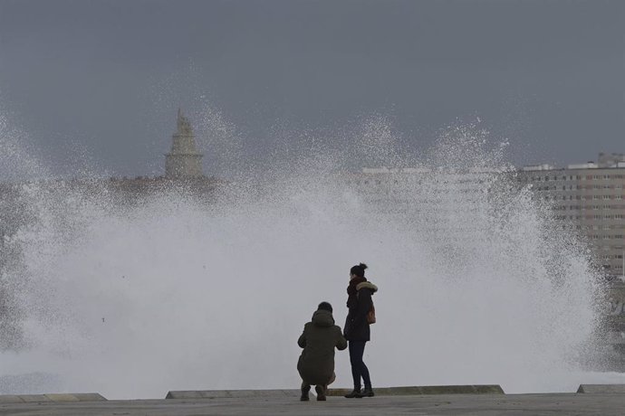 Dos personas observan las olas que rompen en la zona de las Esclavas, en A Coruña.