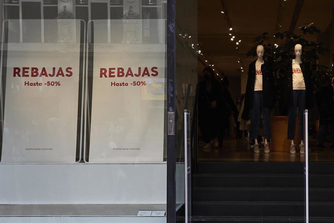 Entrada de una tienda de ropa con carteles de rebajas en una calle comercial del centro de Madrid