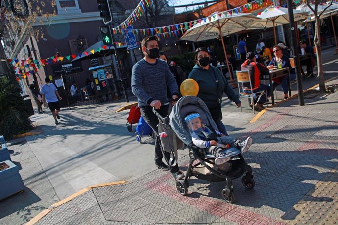 Archivo - Una familia pasea con mascarilla por Santiago
