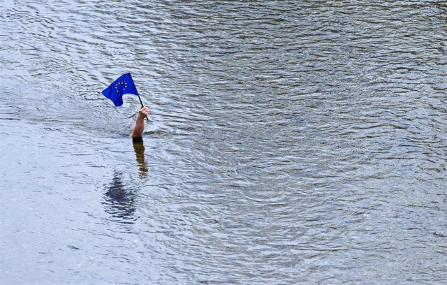 13 December 2021, Bavaria, Munich: A submeged figure of a person holds up the EU flag against the water current of the Isar river as part of The Patriot art installation by Christian Schnurrer. Photo: Sven Hoppe/dpa - ACHTUNG: Nur zur redaktionellen Verwe