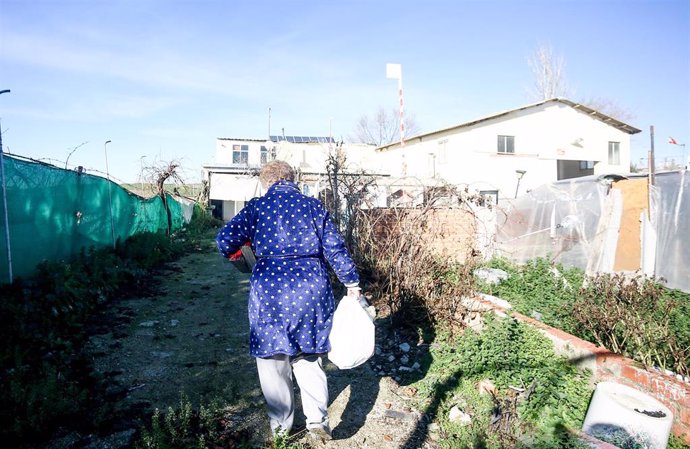 Una mujer camina con bolsas que ha recogido en la entrega de regalos y alimentos organizada por la Fundación Madrina, en la Cañada Real, a 31 de diciembre de 2021, en Madrid, (España). La entrega de regalos y comida va dirigida para los niños de familia