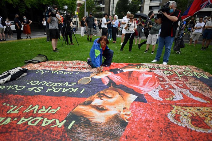 Supporters unfurl a banner outside the Park hotel quarantine facility where it is believed Serbian tennis player Novak Djokovic is being detained in Melbourne, Friday, January 7, 2022. World No.1 tennis star Novak Djokovic is fighting his visa cancellat