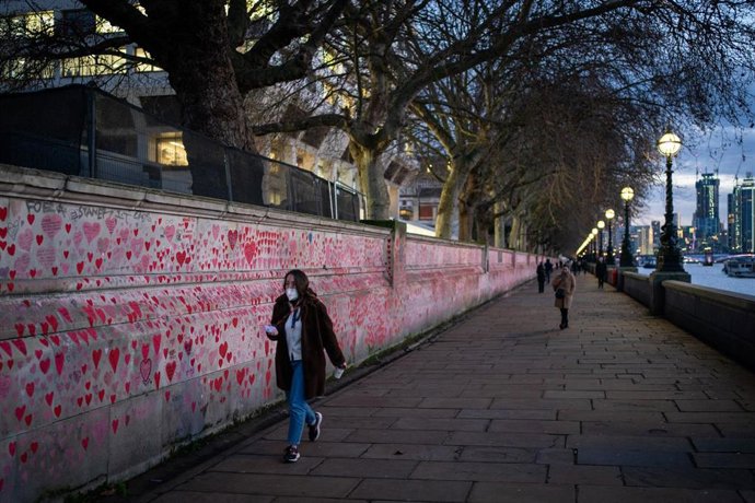 04 January 2022, United Kingdom, London: A woman passes the National Covid Memorial Wall, in Westminster at dusk as the UK recorded more than 200,000 coronavirus cases in a day for the first time. Photo: Dominic Lipinski/PA Wire/dpa