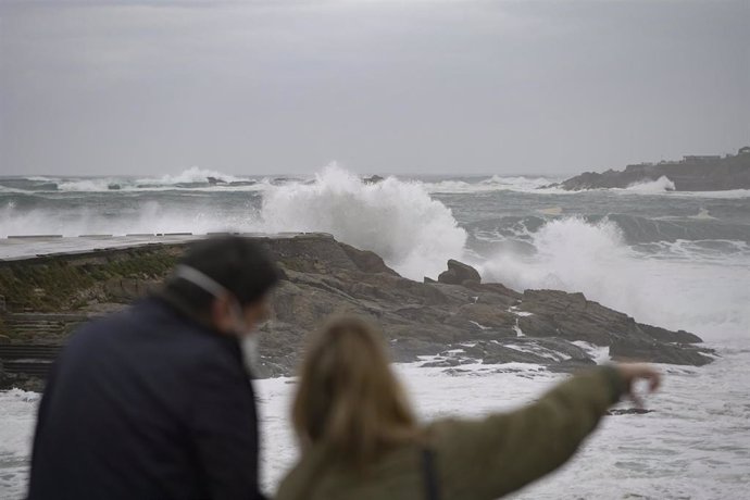 Dos personas observan el fuerte oleaje en la costa en A Coruña, a 8 de enero de 2022, en A Coruña