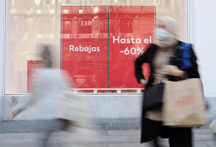 Varias personas pasan delante del escaparate de H&M.