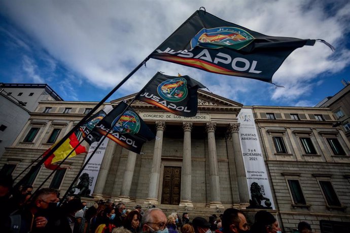 Archivo - Varias personas sostienen banderas de la plataforma Jusapol en la manifestación en Madrid contra la reforma de la 'ley mordaza'