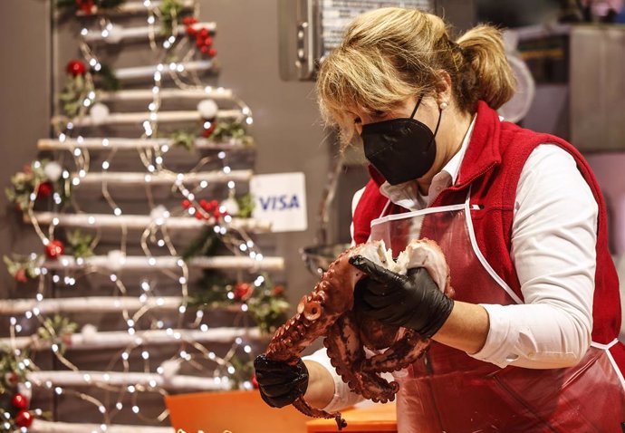 Una vendedora con un pulpo en el Mercado Central de Valencia, a 23 de diciembre de 2021, en Valencia, Comunidad Valenciana (España). Para evitar la concentración de personas que comprar los productos durante los días previos a la Navidad, el Mercado Cen
