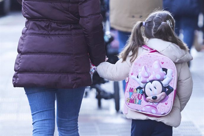 Una niña, acompañada de un madre, durante la vuelta al colegio de los niños tras las vacaciones de Navidad con la aplicación de las nuevas restricciones dependiente de cada comunidad autónoma, a 10 de enero de 2022 en Sevilla (Andalucía, España)