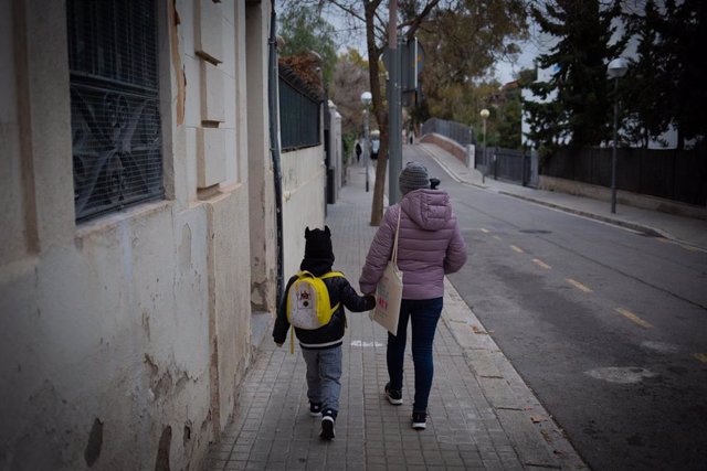 Una mujer lleva de la mano a un niño a su primer día de clase presencial tras la Navidad