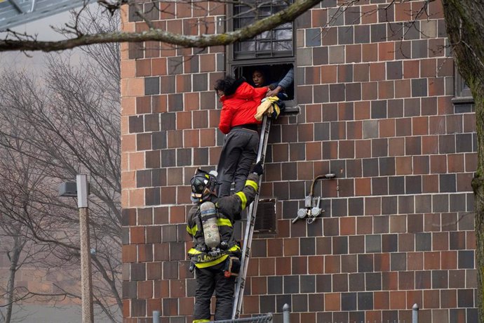 Bomberos durante la evacuación de vecinos de un edificio afectado por un incendio en el barrio del Bronx de Nueva York