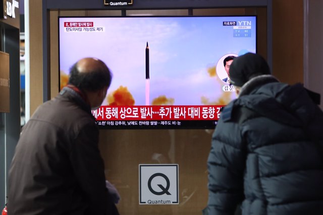 Dos hombres viendo en una televisión norcoreana el lanzamiento de un misil