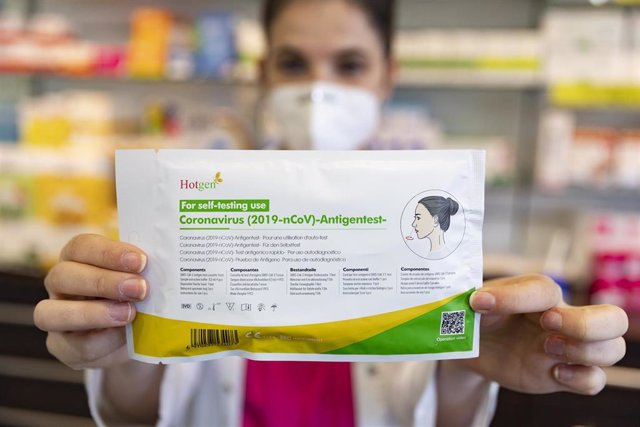 Una farmacéutica muestra un test de antígenos en una farmacia, foto de recurso