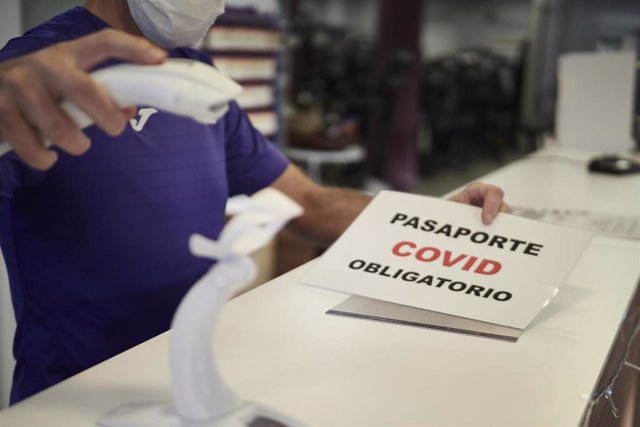 Un trabajador escanea el pasaporte Covid a una usuaria, en su gimnasio, el día en que han entrado en vigor nuevas restricciones por el coronavirus, a 29 de diciembre, en Pamplona, Navarra, (España).
