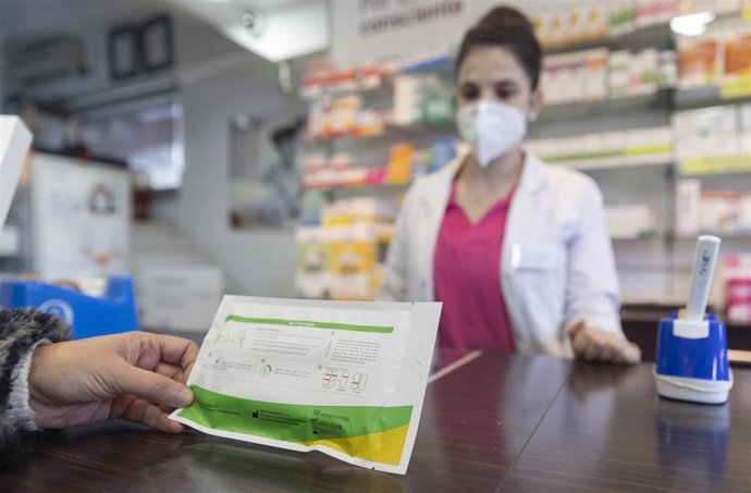 Una mujer con un test de antígenos en un farmacia