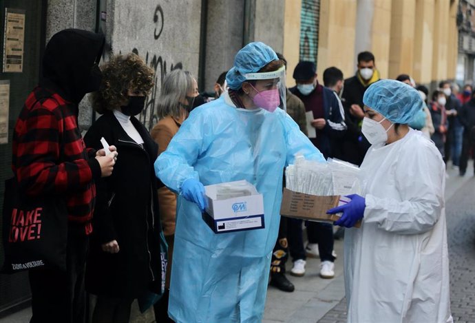 Dos sanitarias recogen test de Covid-19 de las personas que hacen cola en el Centro de Salud Universidad, a 21 de diciembre de 2021, en Madrid, (España).