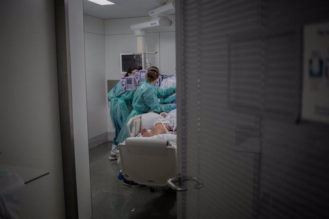 Archivo - Personal sanitario visita a un enfermo ingresado en una habitación de una Unidad de Cuidados Intensivos, foto de recurso