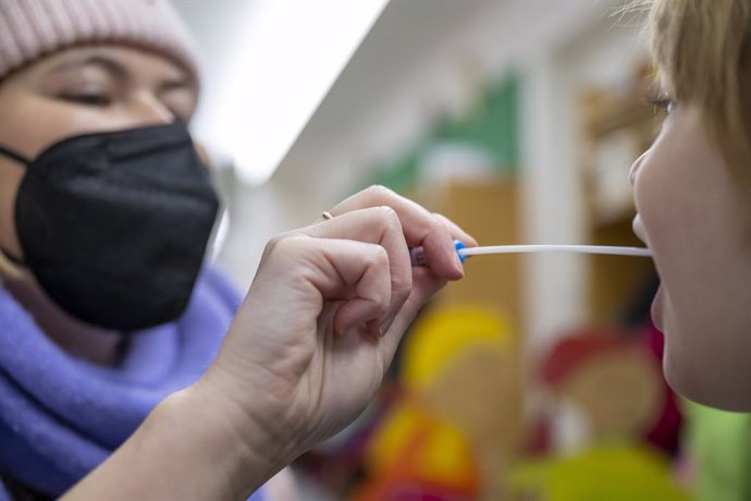 10 January 2022, Bavaria, Munich: A woman takes a Lollitest swab from a child at the entrance to the Montessori Center daycare center. The German Paul Ehrlich Institute stated that a large part of the rapid tests to detect corona available in Germany ar