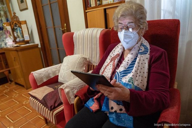 Archivo - Una mujer de edad avanzada lee en una tablet