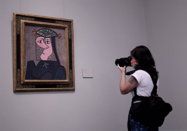 Archivo - Una mujer realiza una fotografía de la obra 'Busto de mujer 43', de Pablo Picasso, el día de la presentación de la instalación en el Museo del Prado