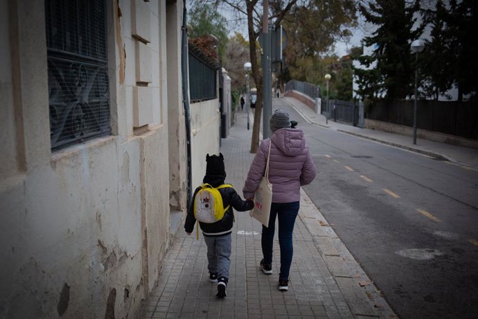 Una dona porta un nen a classe