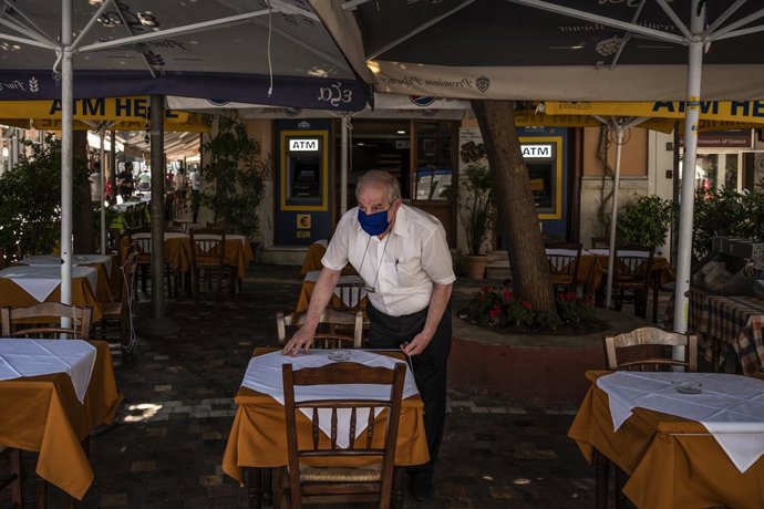 Archivo - 25 May 2020, Greece, Athens: A man wearing a face mask prepares a table in a restaurant, as the cafes and the restaurants are allowed to reopen today after a lockdown due to the spread of the coronavirus pandemic. Photo: Angelos Tzortzinis/DPA