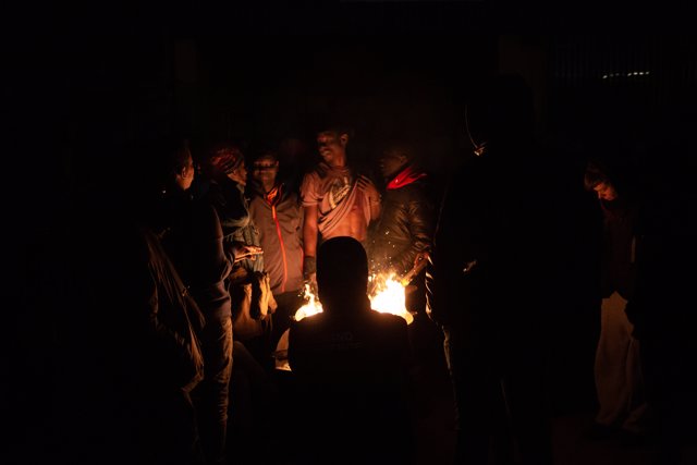 Un grupo de personas entra en calor en el solar perteneciente a nave industrial okupada que se encuentra en desuso en la calle Progrés de Badalona, a 13 de enero de 2022, en Badalona, Barcelona, Catalunya, (España).  