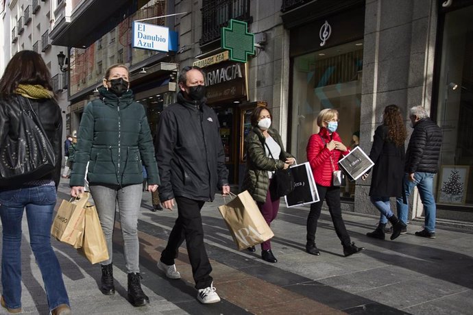 Varias personas con bolsas pasean en una calle comercial del centro de Madrid