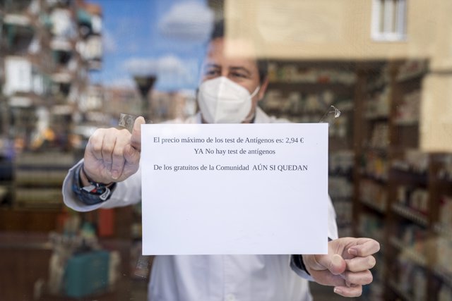 Un farmacéutico coloca un cartel, que indica que pierden dinero con el nuevo precio de los test, en una farmacia en Carabanchel, a 13 de enero de 2022, en Madrid (España).