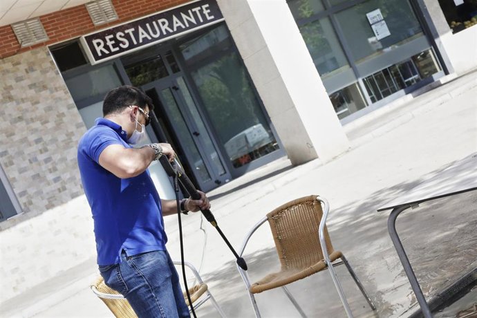 Archivo - Un trabajador desinfecta la terraza de un restaurante.