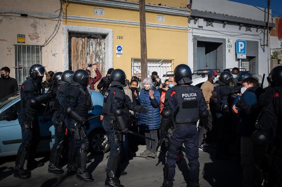 La presidenta de la CUP en el Parlament, Dolors Sabater, y la diputada 'cupaire' Basha Changue ante antidisturbios de los Mossos d'Esquadra que han desalojado una nave de Badalona (Barcelona).