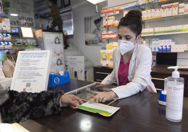 Una farmacéutica muestra un test de antígenos a una persona en la farmacia Las Gemelas, a 10 de enero de 2022, en Madrid (España).