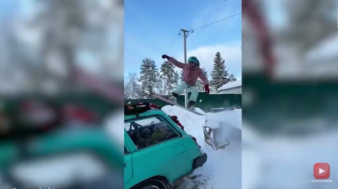 Volando sobre un coche con una tabla de snowboard