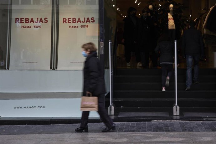 Una persona pasa delante de un escaparate de un comercio con carteles de rebajas,. Archivo.