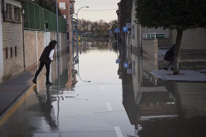 Archivo - Una persona del vecindario cruza una de las calles inundadas, a 12 de diciembre de 2021, en San Adrián.