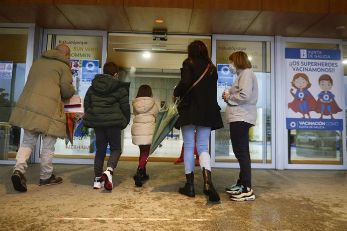 Varios niños acompañados de sus padres, a su llegada al recinto ferial Expourense para ser vacunados.