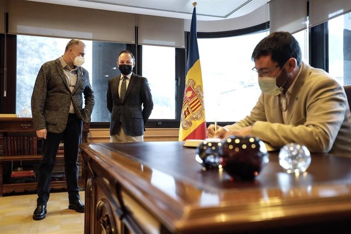 El vicealcalde Jordi Fbrega y el jefe de Gobierno de Andorra, Xavier Espot, conversan mientras el alcalde Francesc Viaplana firma en el libro de honor del Gobierno de Andorra.